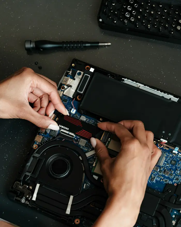 Close-up of hands fitting a part inside an open laptop
